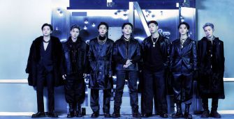 BTS members posing together in stylish black outfits against a blue-themed background.