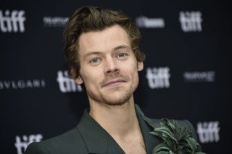 Image of Harry Styles attending an event, smiling at the camera.