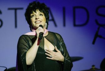 Liza Minnelli performing on stage, wearing a sparkling outfit and smiling while holding a microphone.