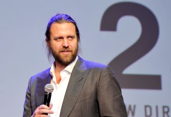 Carl Rinsch speaking at an event, holding a microphone.