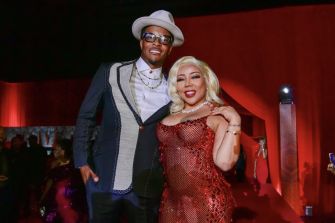 T.I. and Tiny Harris posing at an event, both dressed in formal attire against a red backdrop.