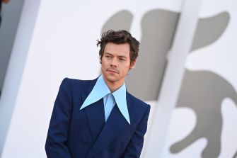 Harry Styles at a public event, wearing a blue suit with a light blue collar.