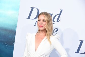 Christina Applegate at a public event, wearing a white outfit and smiling.