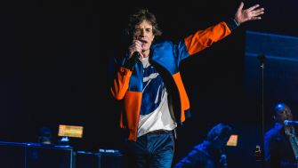 Mick Jagger performing on stage with a microphone, wearing a colorful outfit.