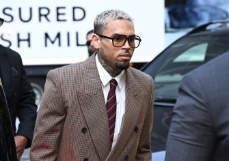 Chris Brown arriving at a court hearing, wearing a suit and glasses.