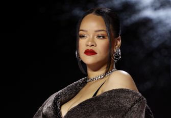 Image of a woman with dark hair and bold red lipstick, wearing a glamorous outfit with earrings and a fur wrap.