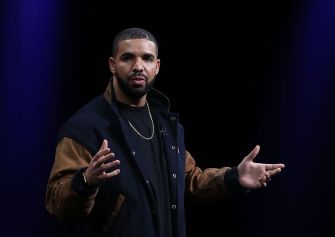 Drake speaking on stage at an event.