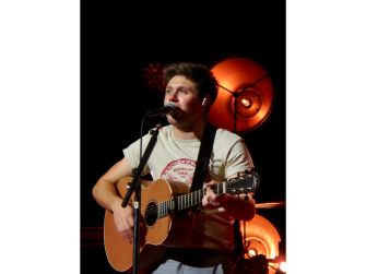 Niall Horan performing on stage with an acoustic guitar.
