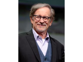 A smiling man with glasses and light gray hair, dressed in a suit, poses for the camera.