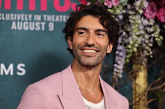 Image of Justin Baldoni, actor and filmmaker, smiling at an event with a floral backdrop.
