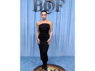 Demi Lovato posing in a black strapless dress at an event with a blue backdrop.