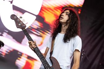 Bassist Dominic DiGesu performing on stage with a bass guitar during a concert.