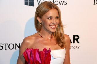 Kylie Minogue smiling at an event, wearing a stylish outfit.