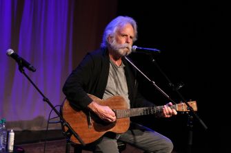 A musician performing on stage with an acoustic guitar.