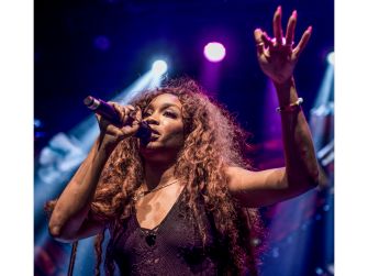 A live performance of SZA with a microphone, passionately engaging with the audience.