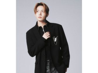 Heeseung from Enhypen poses in a stylish outfit, looking thoughtfully into the distance.