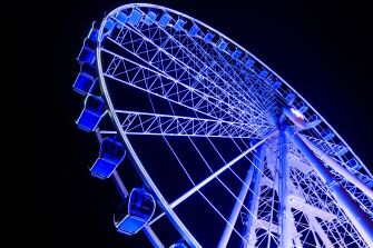 Ferris wheel illuminated at night, featuring enclosed glass cabins.