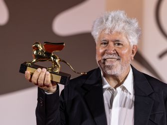 A man holds a trophy resembling a lion statue with wings, smiling at an event.