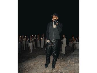 YoungBoy Never Broke Again performing outdoors, surrounded by a group of individuals holding candles.