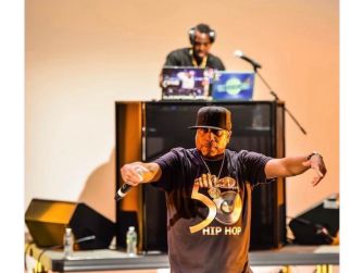 Rob Base performing on stage with a DJ in the background, celebrating hip hop culture.